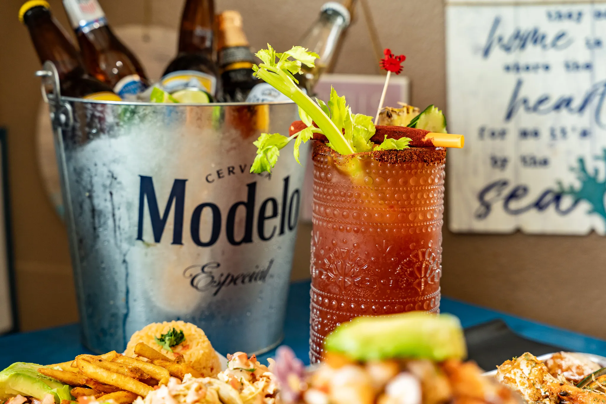 A metal Modelo bucket of iced beers next to a chili-rimmed Michelada at Wacky Crab Shack